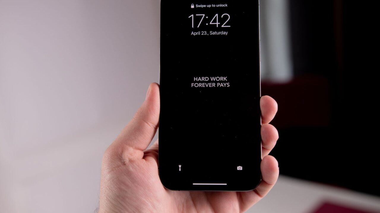 Close-up of a hand holding a smartphone displaying the motivational quote 'Hard Work Forever Pays.'