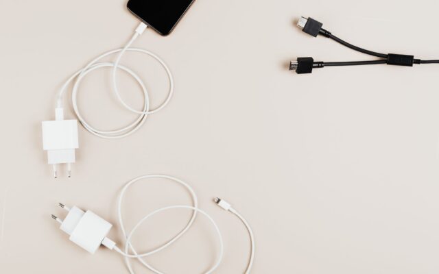 Flat lay of mobile devices with chargers and cables on a neutral background.