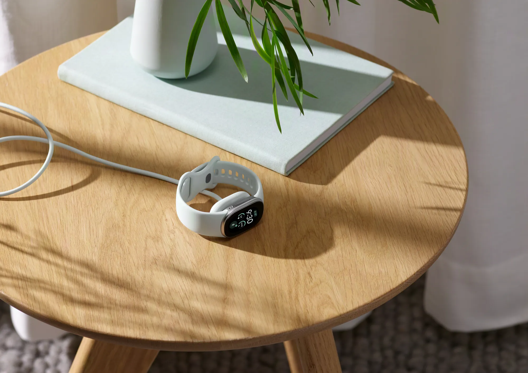 The image shows a Fitbit Edge charging on a side table.