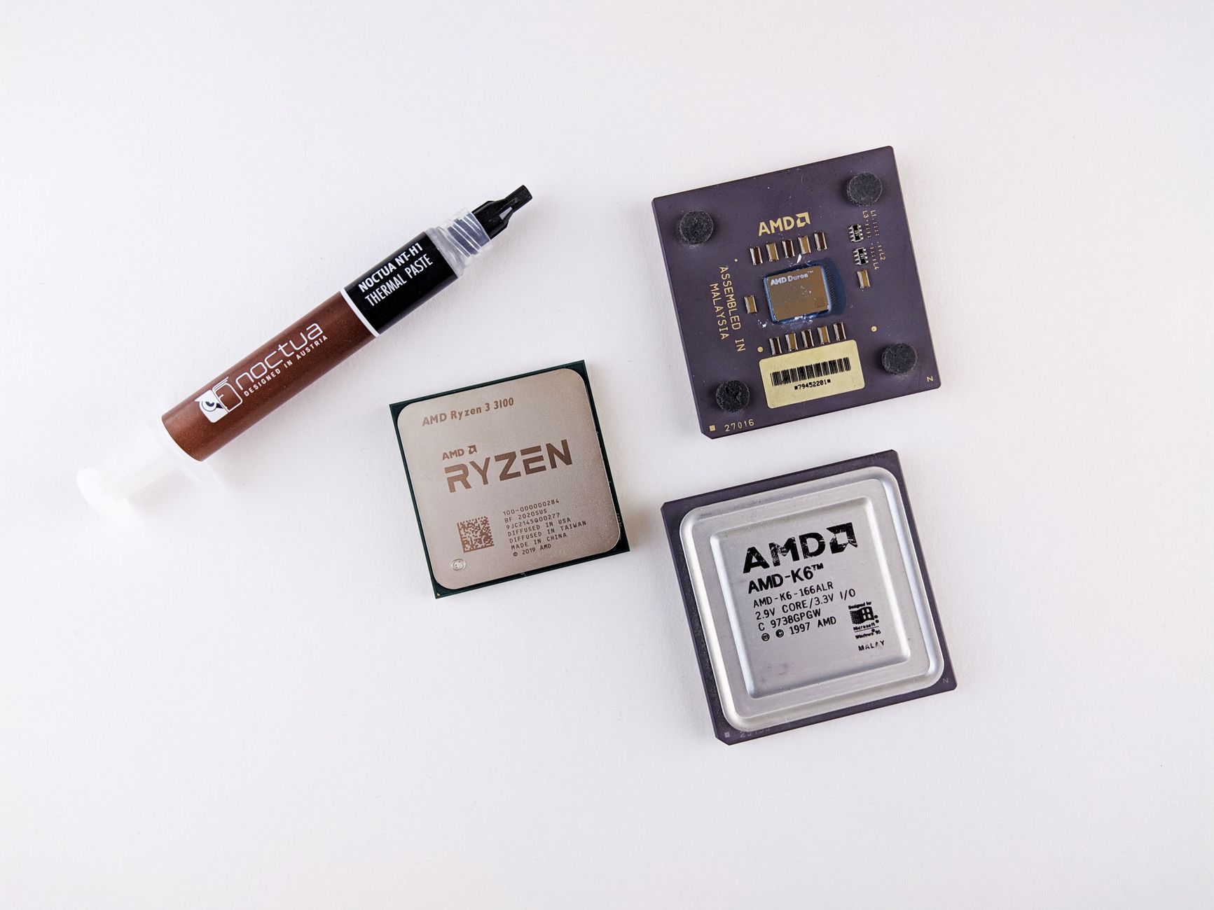 AMD processors and a tube of thermal paste on a white surface