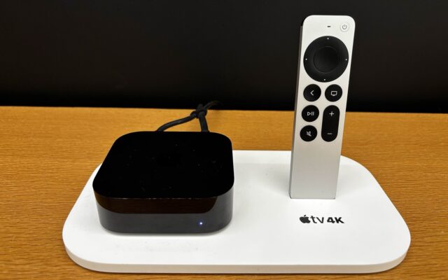An Apple TV 4K and its Siri Remote on a display stand