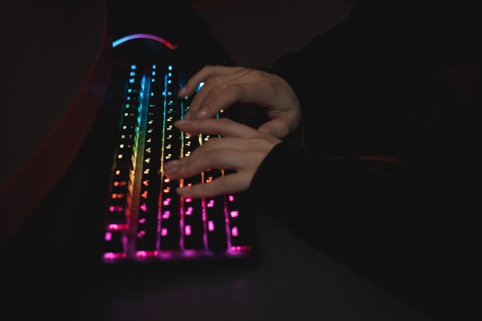 Hands typing on a colorful RGB keyboard