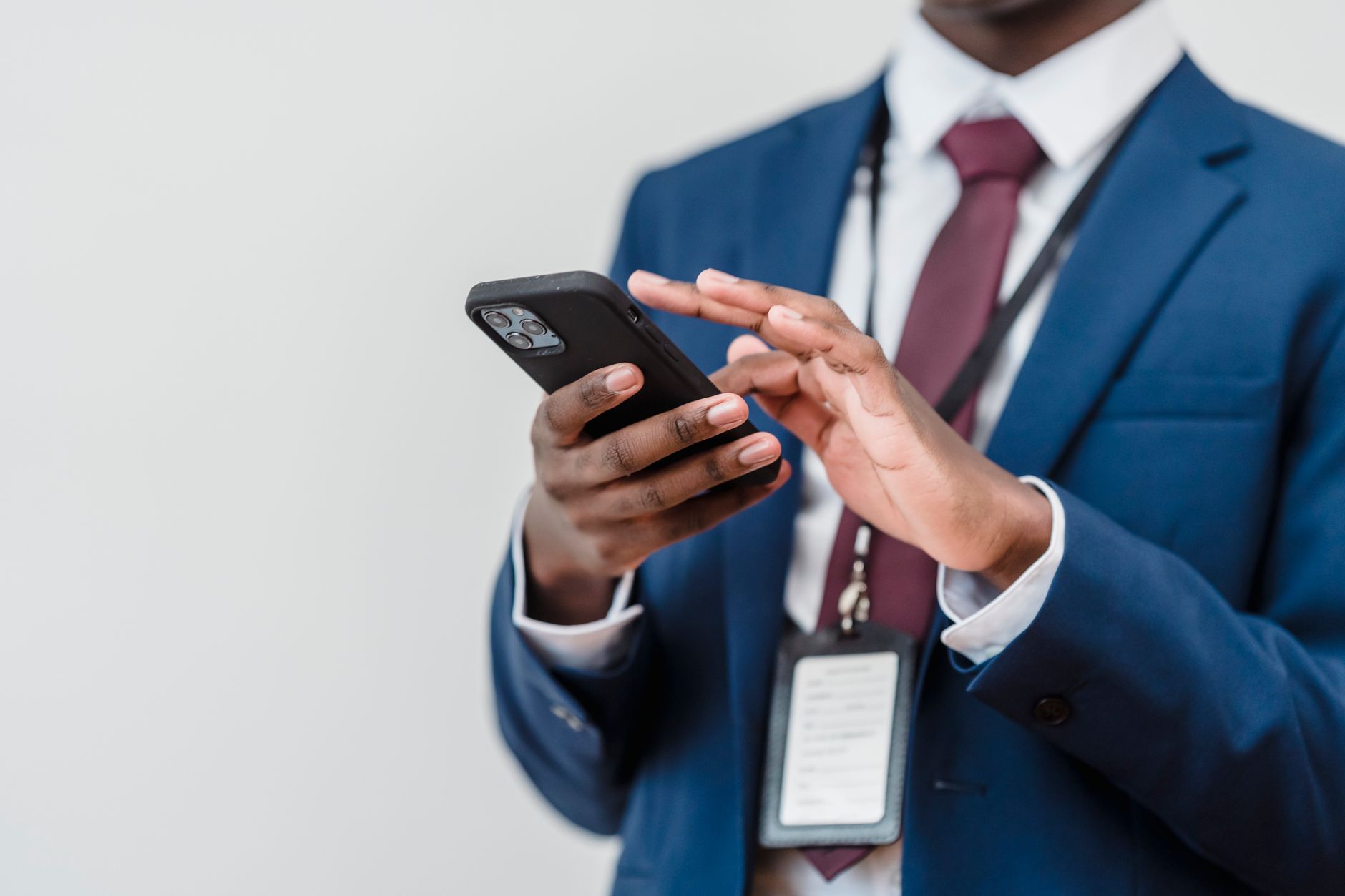 A business professional in a suit using a smartphone indoors, focused on screen interaction.