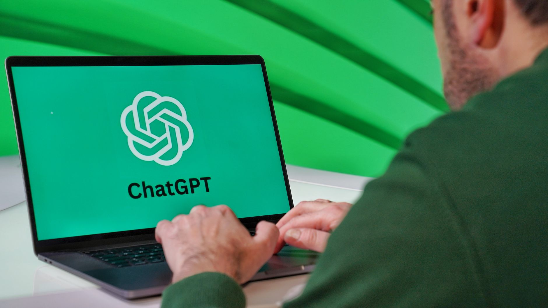 A person typing on a laptop showing the ChatGPT logo