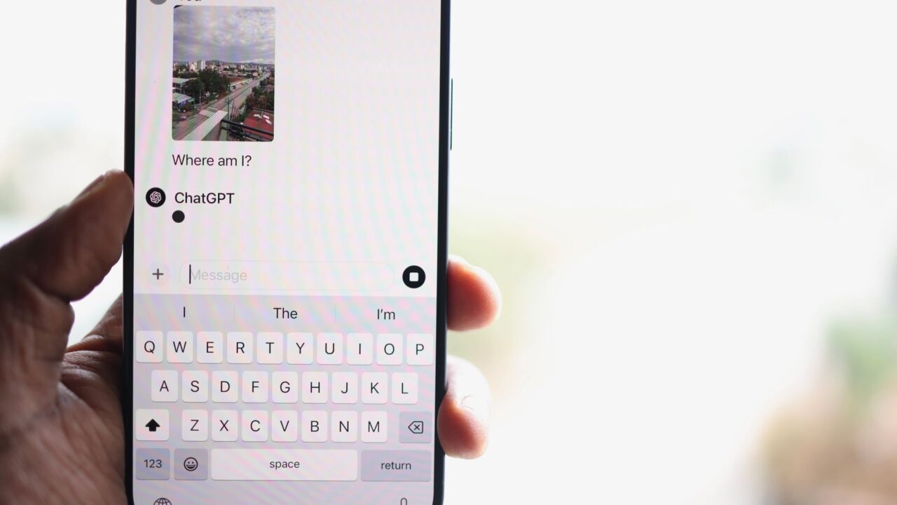 A person holding an iPhone with a ChatGPT conversation on screen