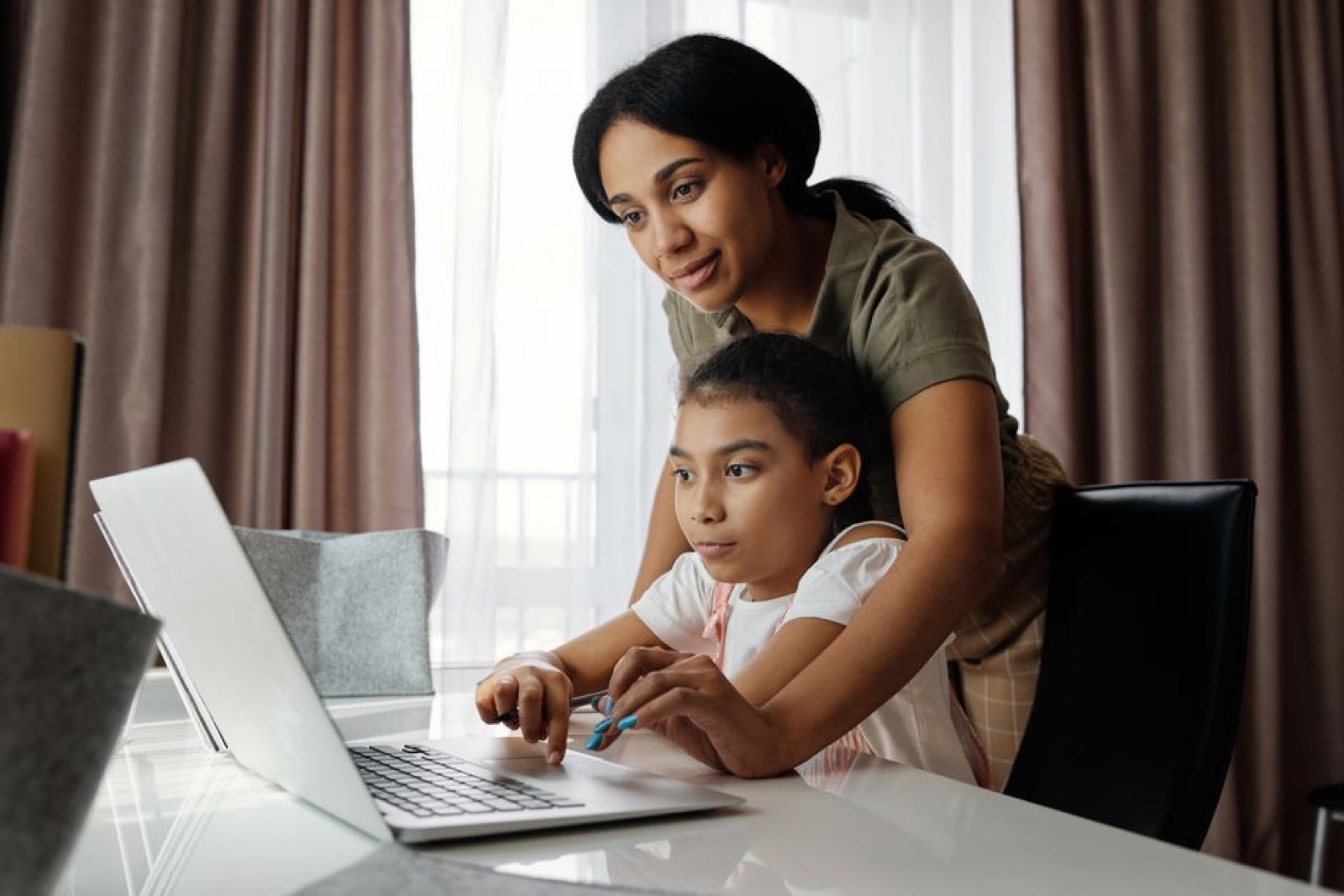 A mother helping her daughter with an online game