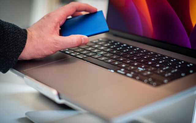 A hand holding a portable drive over a laptop keyboard