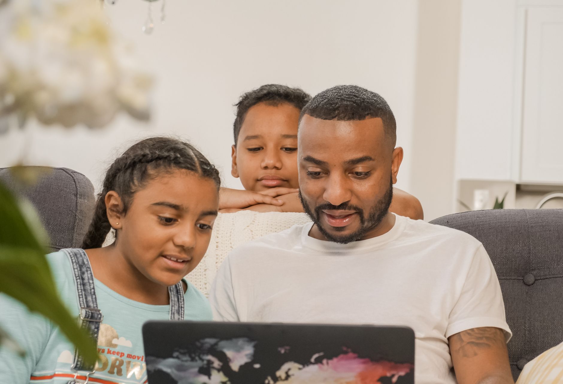 A father and two children using a laptop together at home