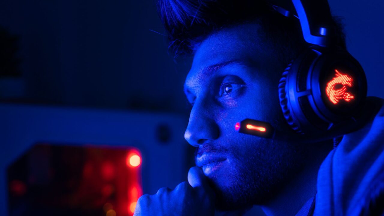 A gamer wearing a headset with a microphone in blue light