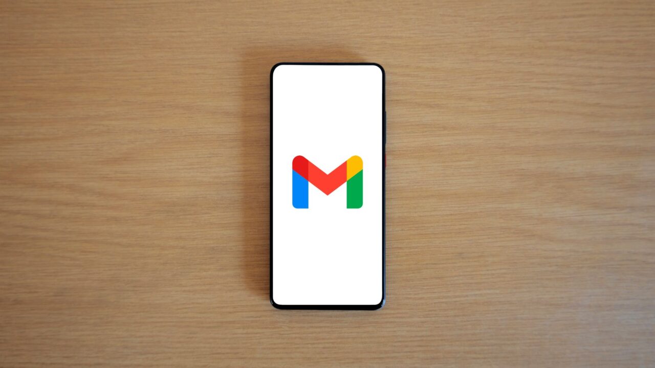 A smartphone showing the Gmail logo on a wooden table