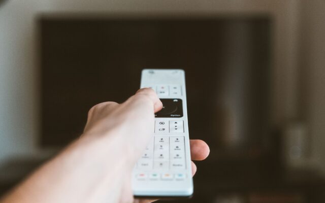 A hand pointing a remote control at a TV