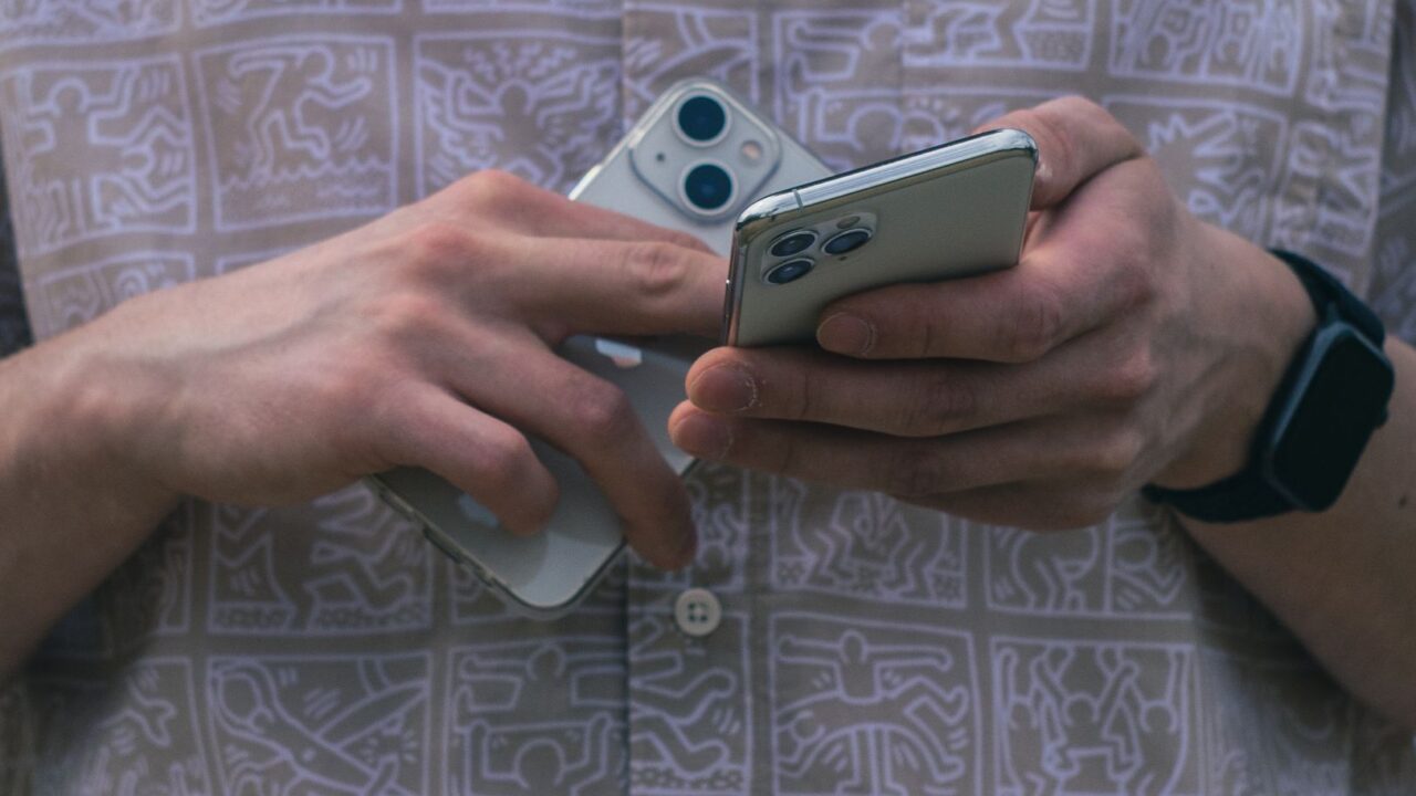 Hands holding two iPhones at once