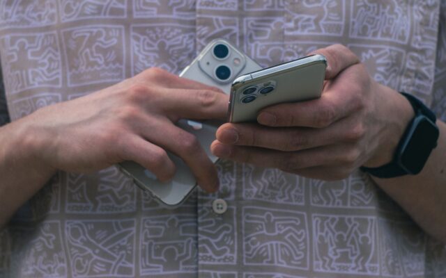 Hands holding two iPhones at once
