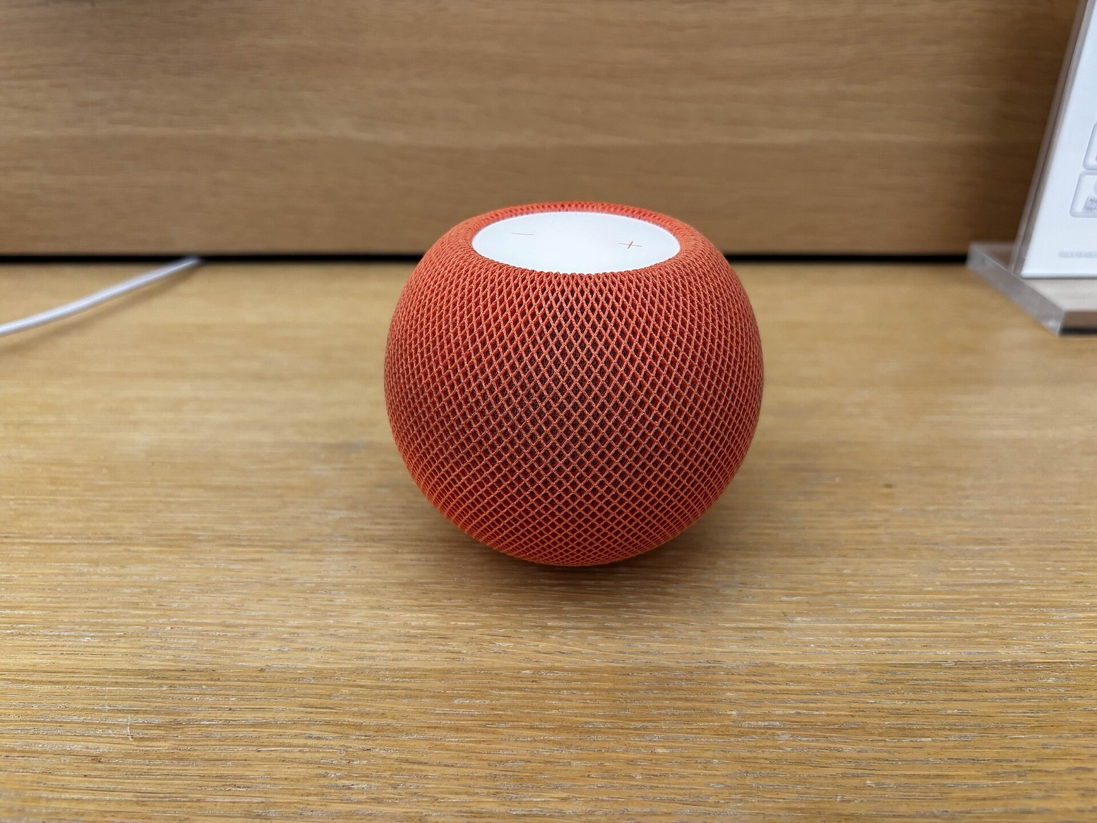 An orange HomePod mini on a wooden table