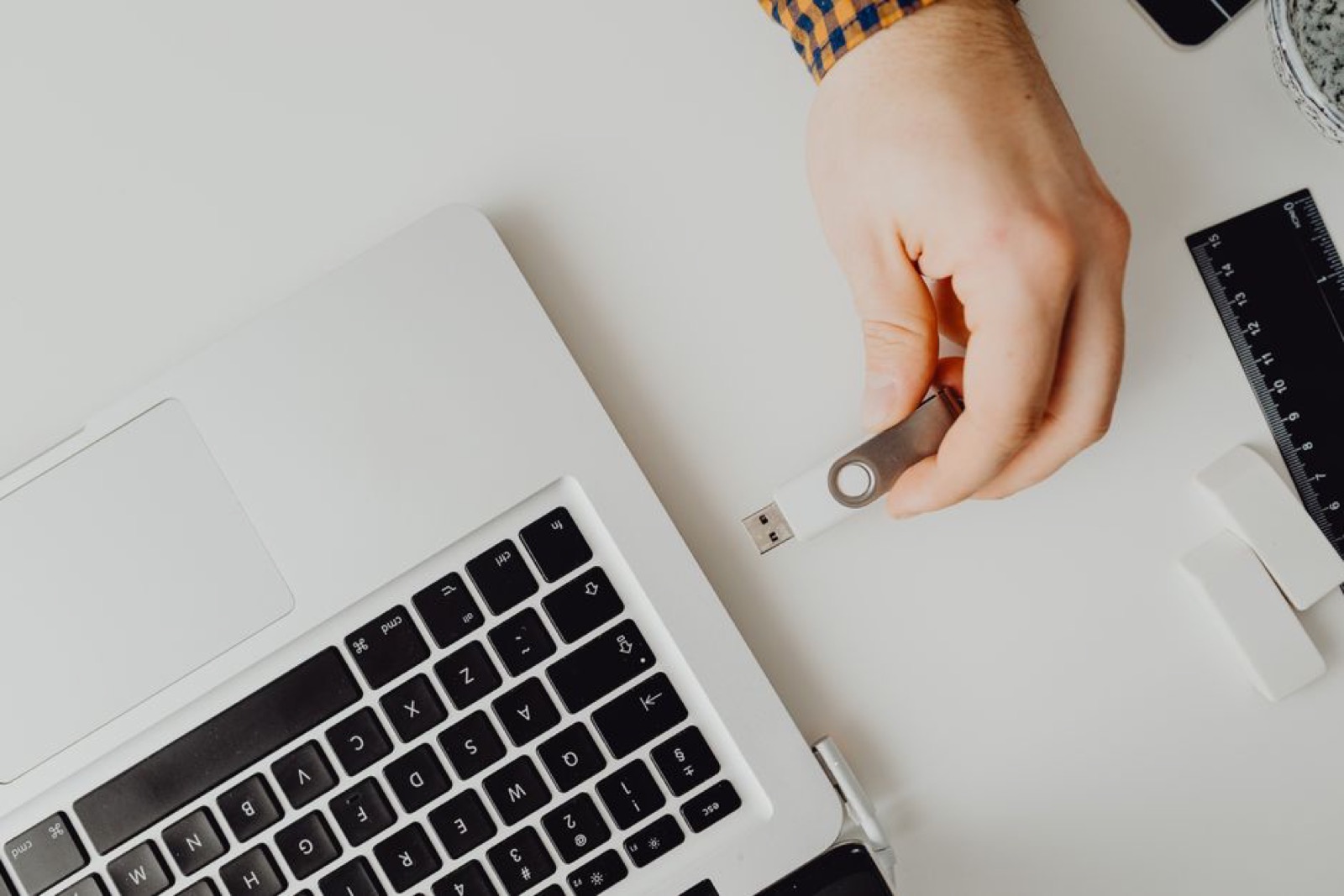 A hand plugging a USB flash drive into a laptop