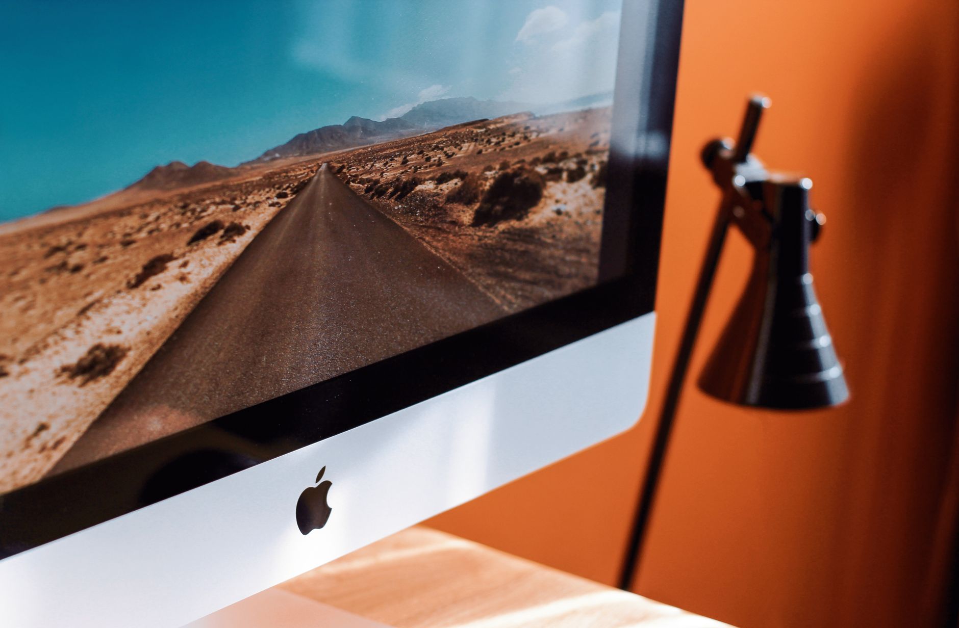 An iMac on a desk next to a black lamp