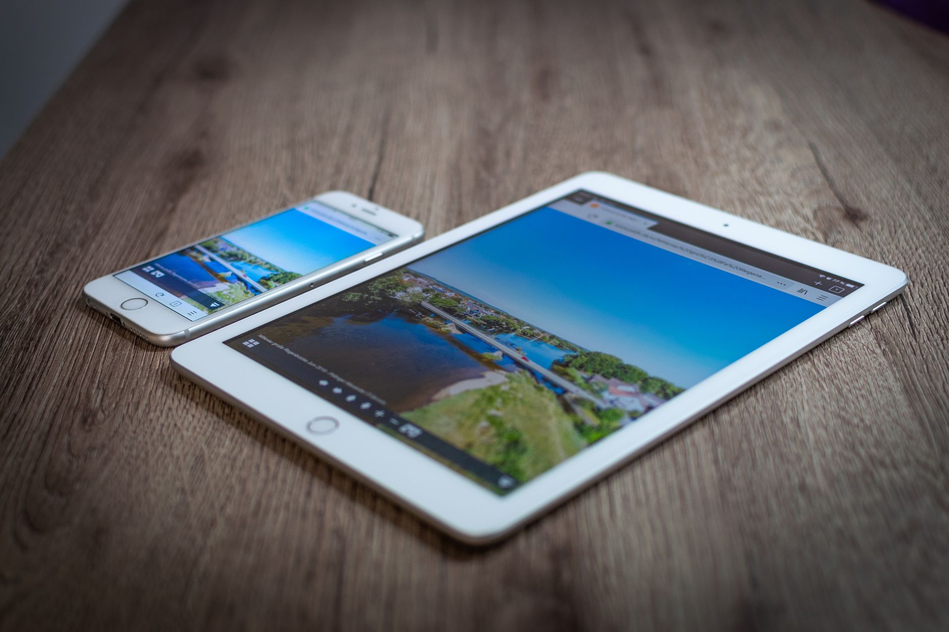 An iPad and an iPhone side by side on a wooden table