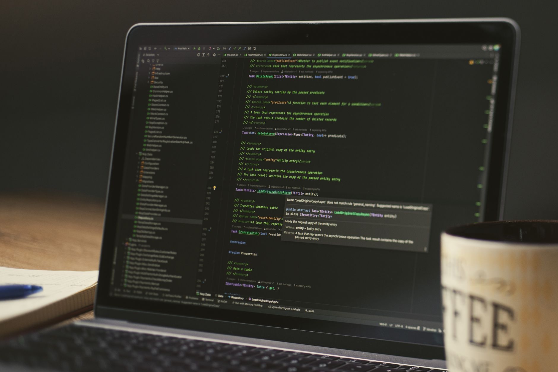 A laptop showing code in an editor next to a coffee mug