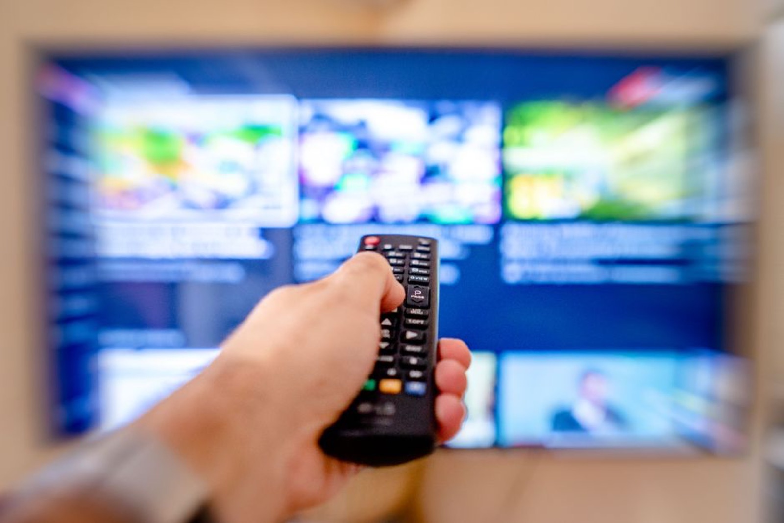 A hand pointing a remote control at a TV