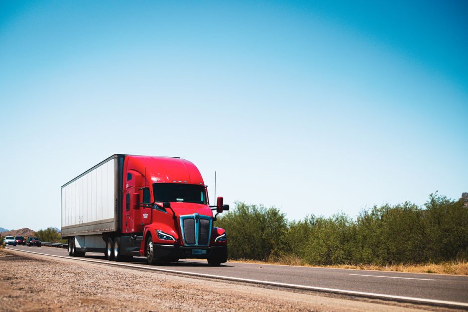 A red semi-truck pulling a trailer on a highway