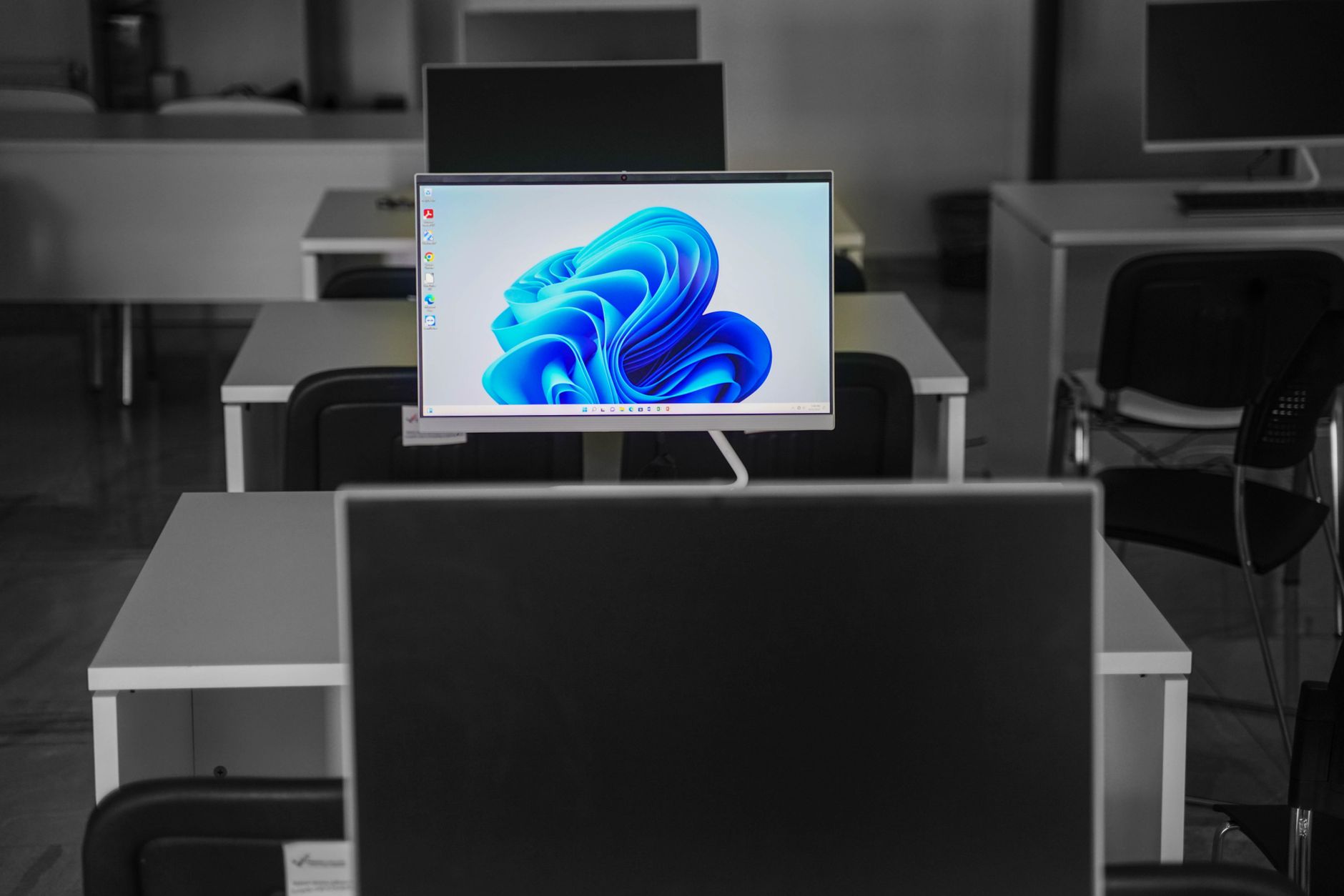 An office desk with a monitor showing the Windows 11 wallpaper