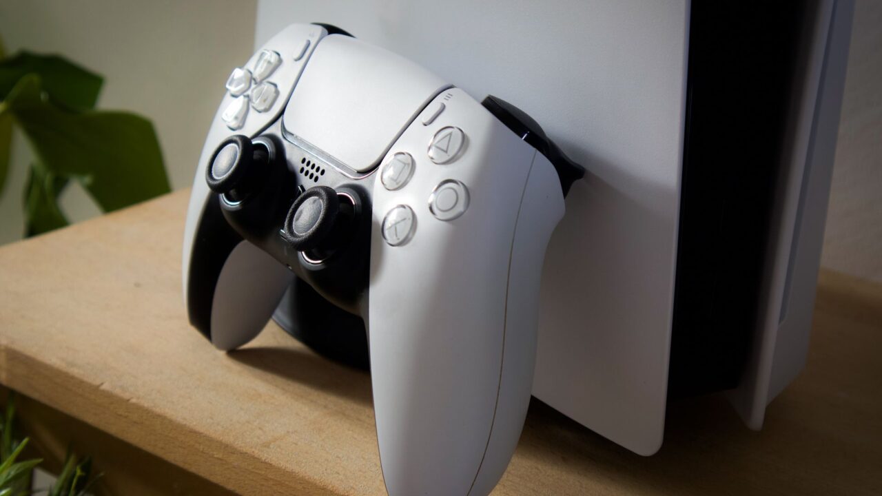A PlayStation 5 with a DualSense controller on a shelf