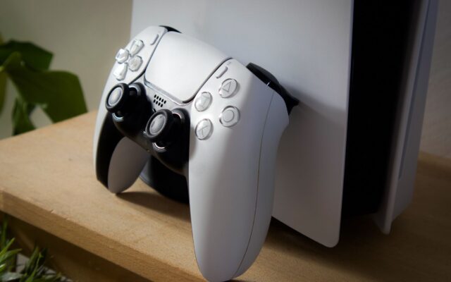 A PlayStation 5 with a DualSense controller on a shelf