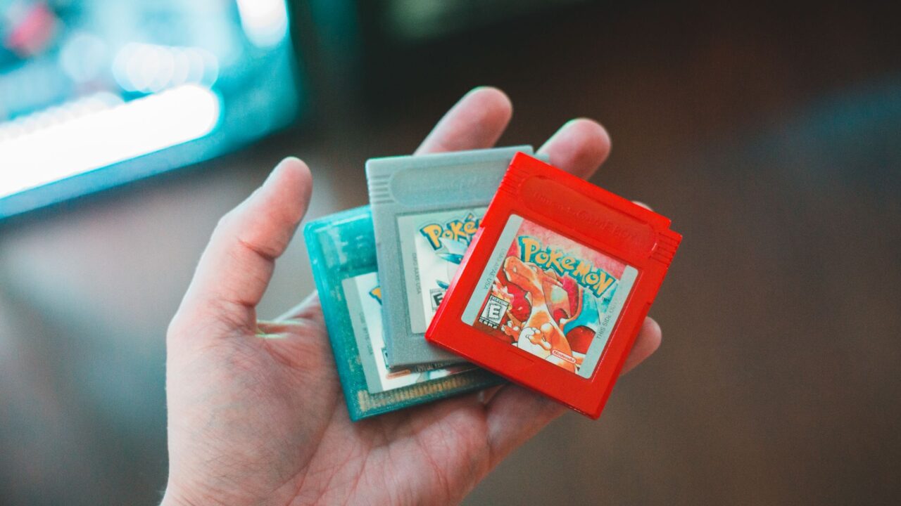 A hand holding Pokémon Game Boy cartridges