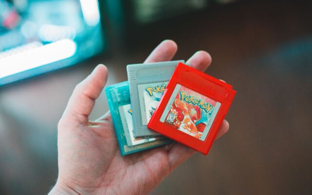 A hand holding Pokémon Game Boy cartridges