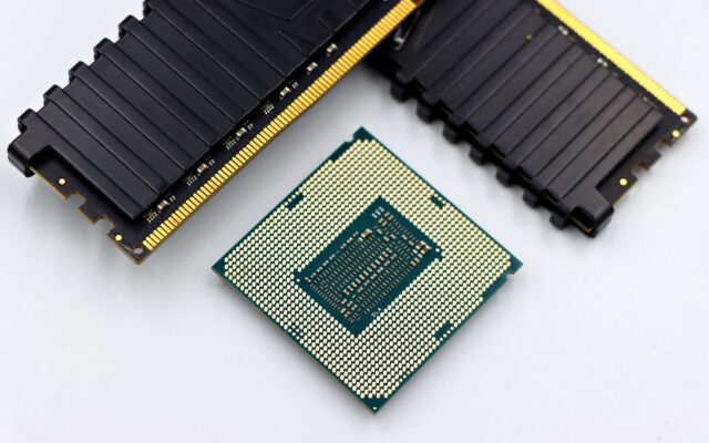 A CPU and RAM sticks displayed on a white surface, showcasing computer hardware components.