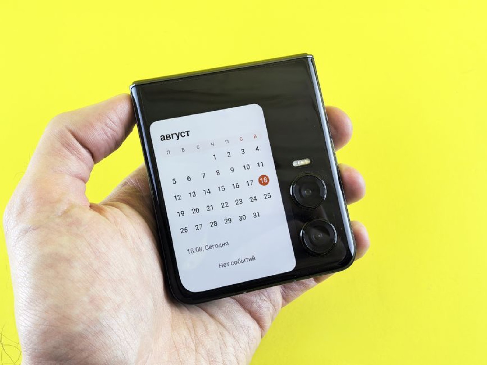 A hand holding a flip smartphone