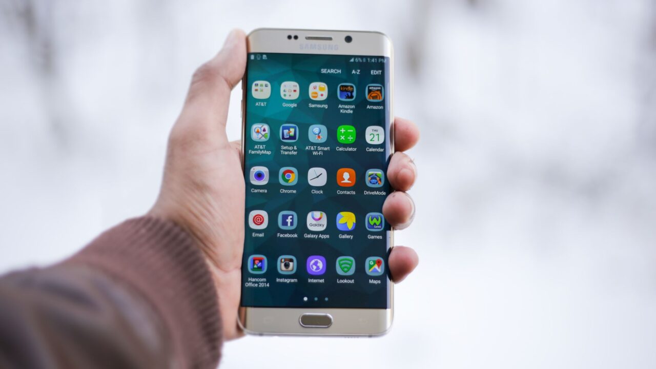 A hand holding a Samsung Galaxy phone showing its apps
