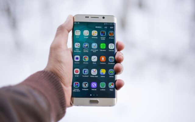 A hand holding a Samsung Galaxy phone showing its apps