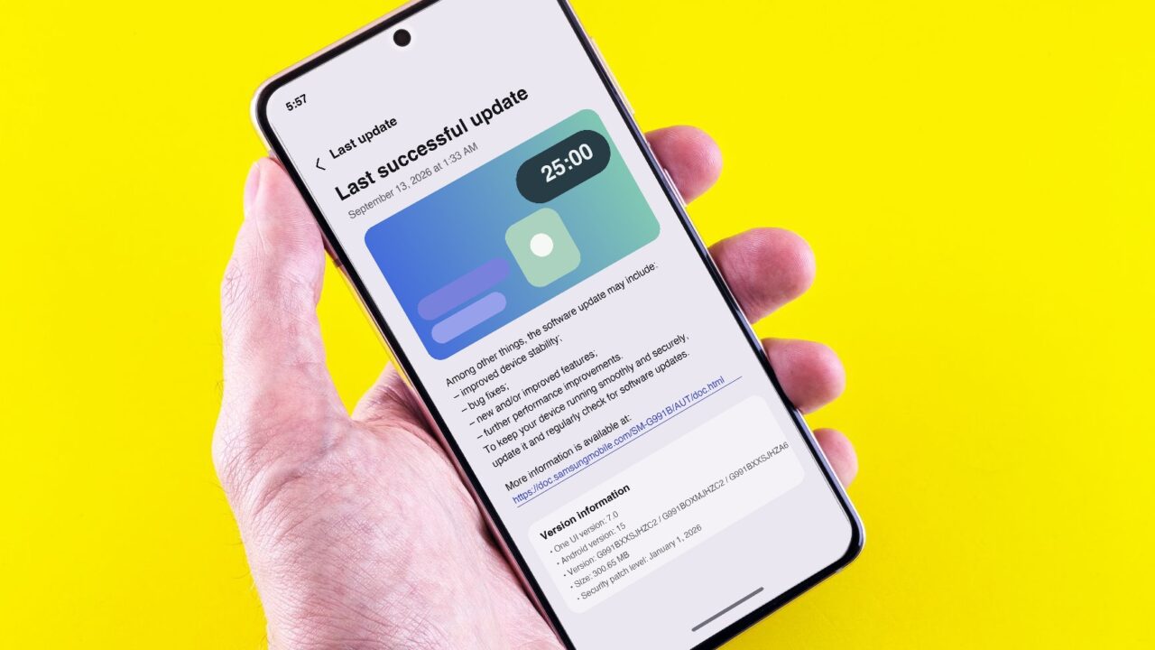 A hand holding a Samsung Galaxy phone showing the software update screen