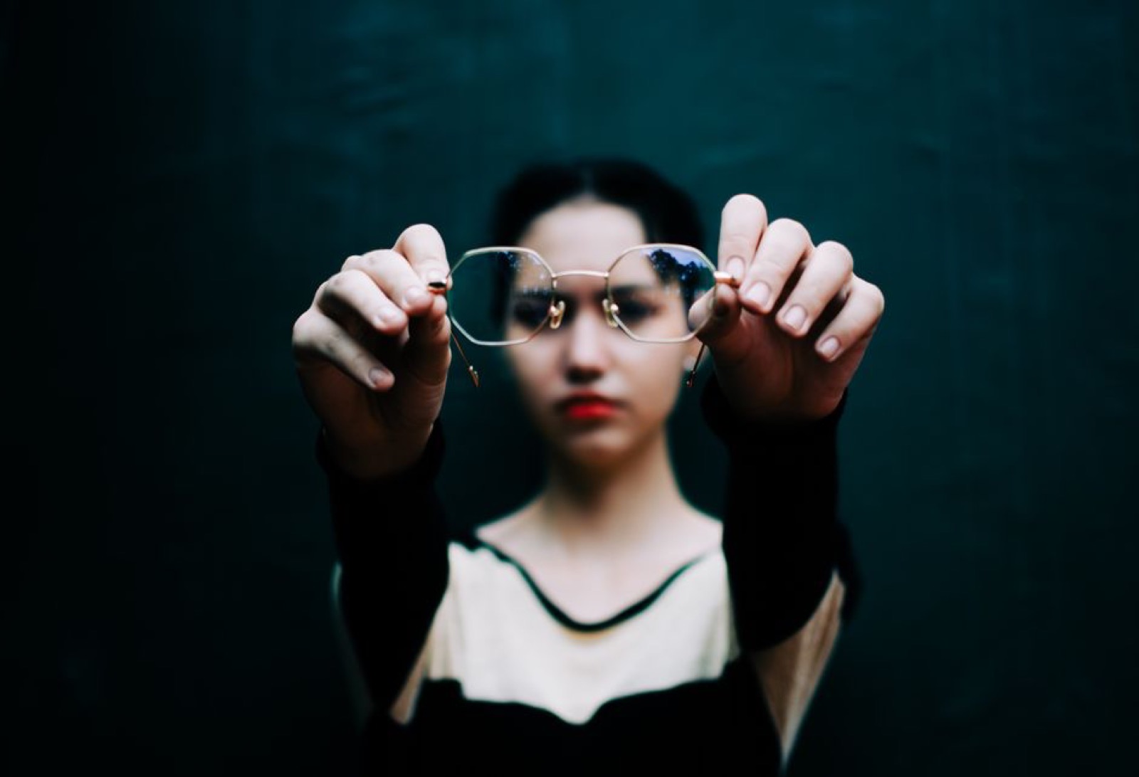 A person holding a pair of eyeglasses