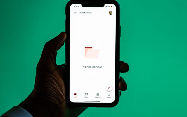 A hand holding a smartphone with an email app open