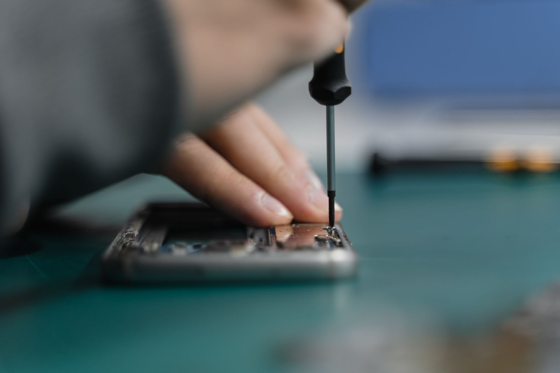 A technician repairing a smartphone with a screwdriver