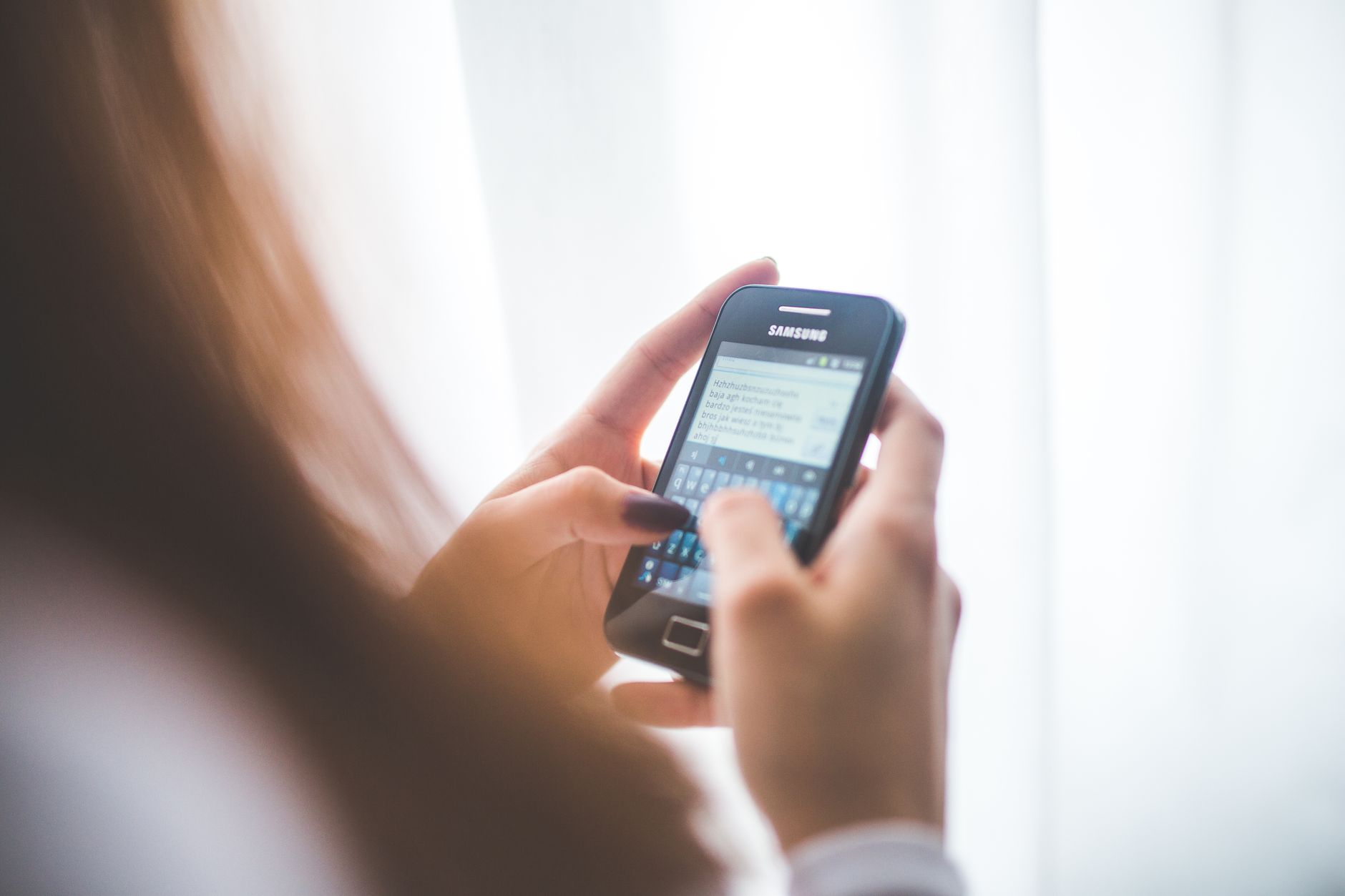 A woman typing a text message on a Samsung phone