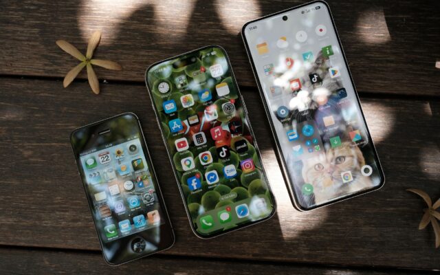 Three smartphones lying on a wooden table