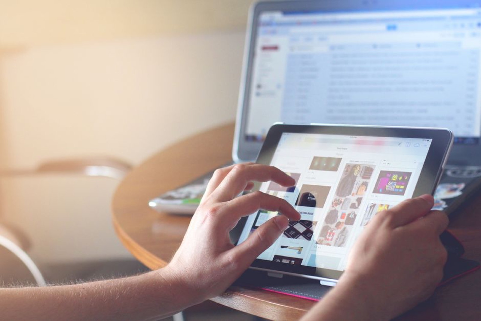 Hands using a tablet beside a laptop