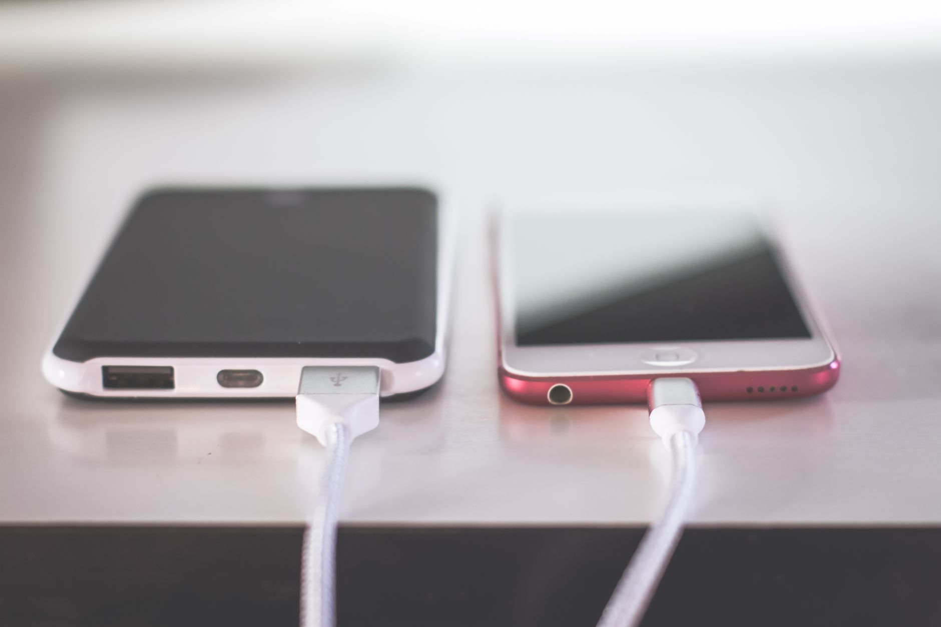 Two smartphones charging side by side on a desk