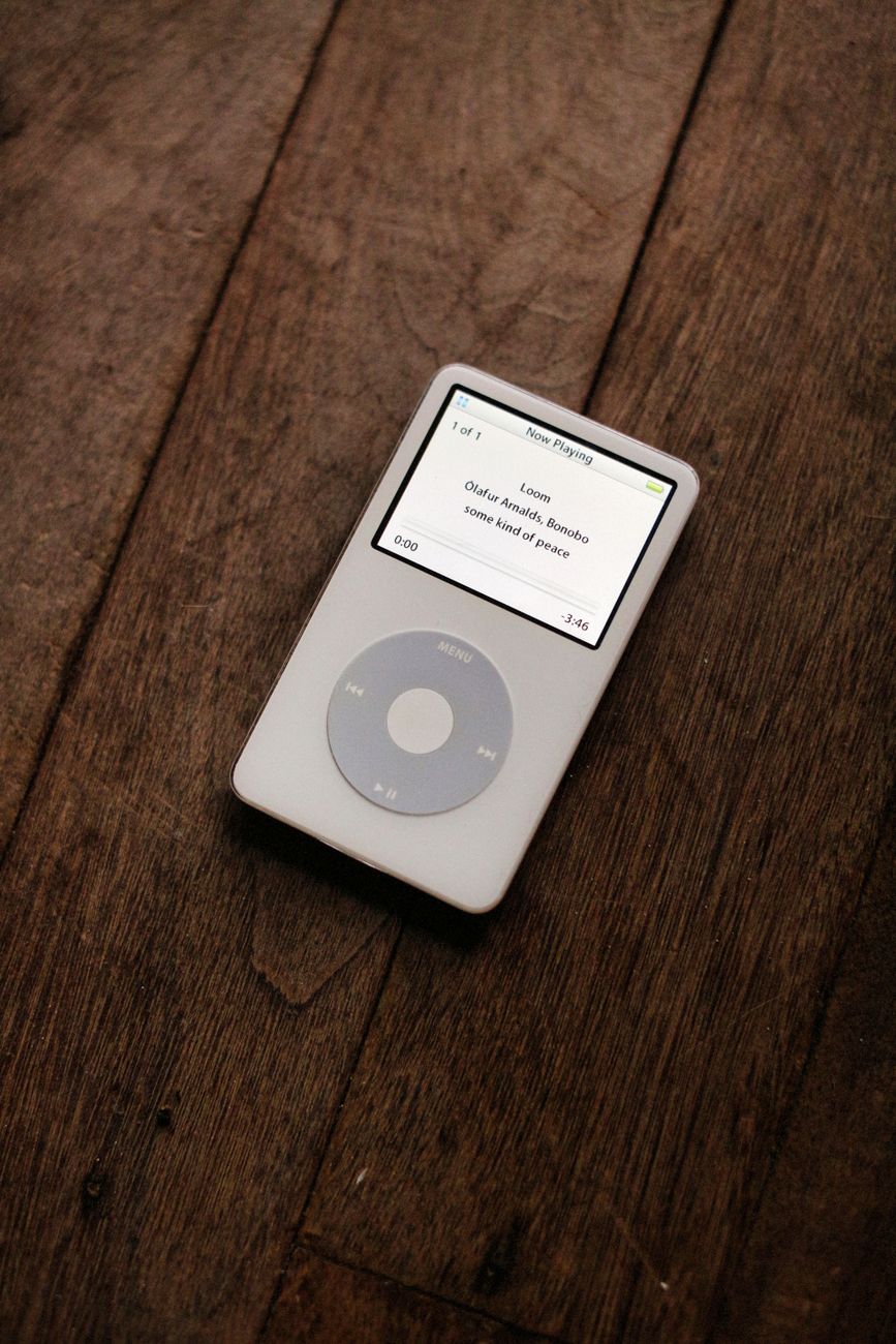 A white iPod with a click wheel on a wooden surface